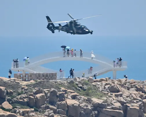 Fujian, one of the closest points to Taiwan from mainland China, on August 4, 2022, ahead of a large-scale military exercise off the coast of Taiwan in response to U.S. House Speaker Nancy Pelosi's visit to the autonomous government. Tourists watch as a Chinese military helicopter passes over the province's Pingtan Island. island.  - China plans to launch its largest-ever military exercise encircling Taiwan in a show of military power across a vital international shipping lane, following U.S. House Speaker Nancy Pelosi's visit to the autonomous island on August 4. .  (Photo by Hector Retamal/AFP) (Photo by Hector Retamal/AFP via Getty Images)