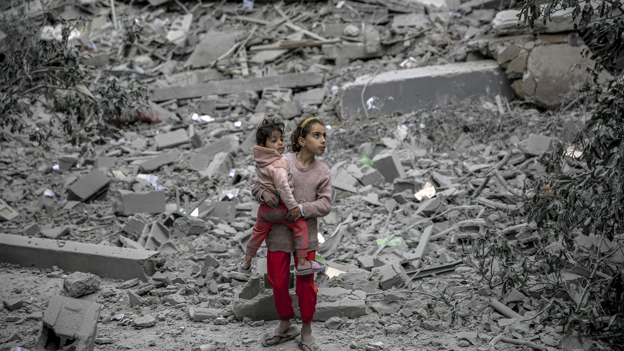 A Palestinian girl carries a child through the rubble of houses destroyed by Israeli bombardment in Gaza on March 3.