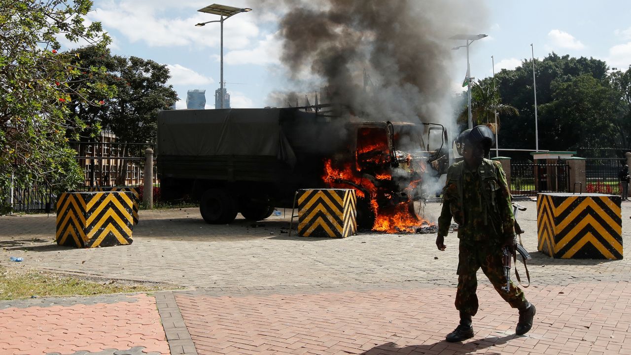 A police officer stands near a burning vehicle during a demonstration against Kenya's proposed finance bill in Nairobi, Kenya, on June 25.