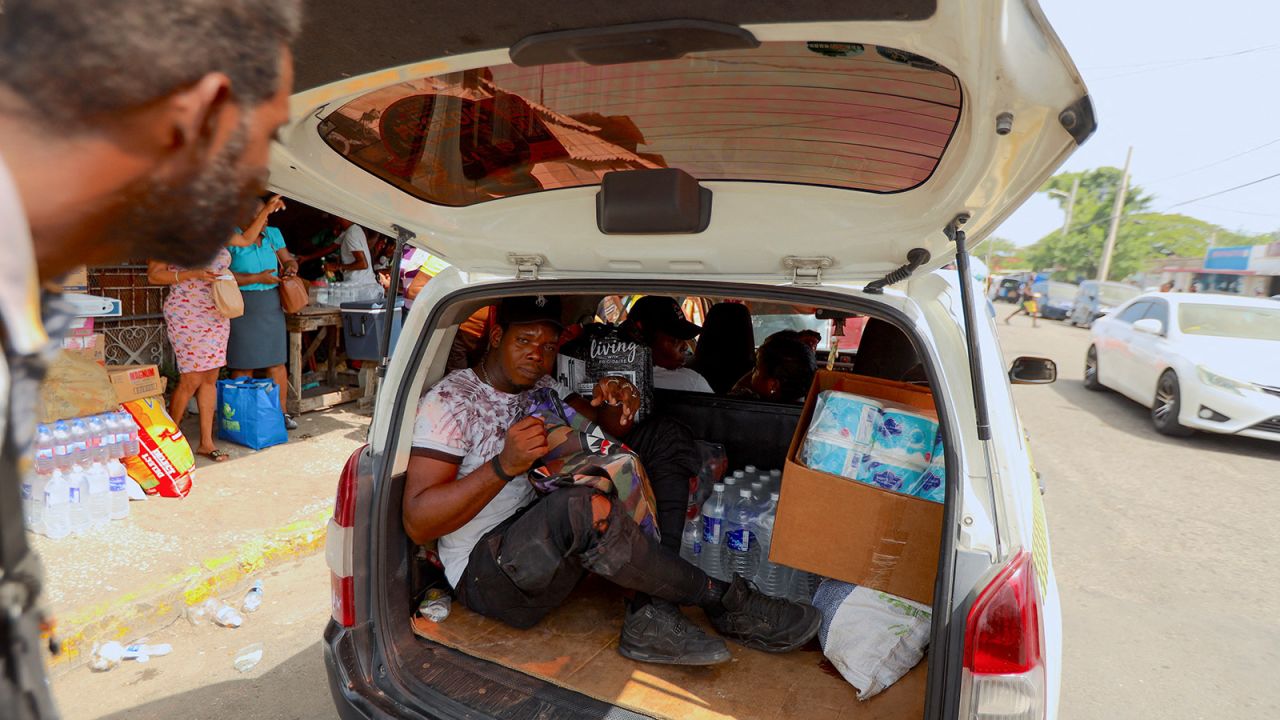 A man gets into the back of a taxi filled with water and perishables, as people prep for Hurricane Beryl in Kingston, Jamaica, on July 2.