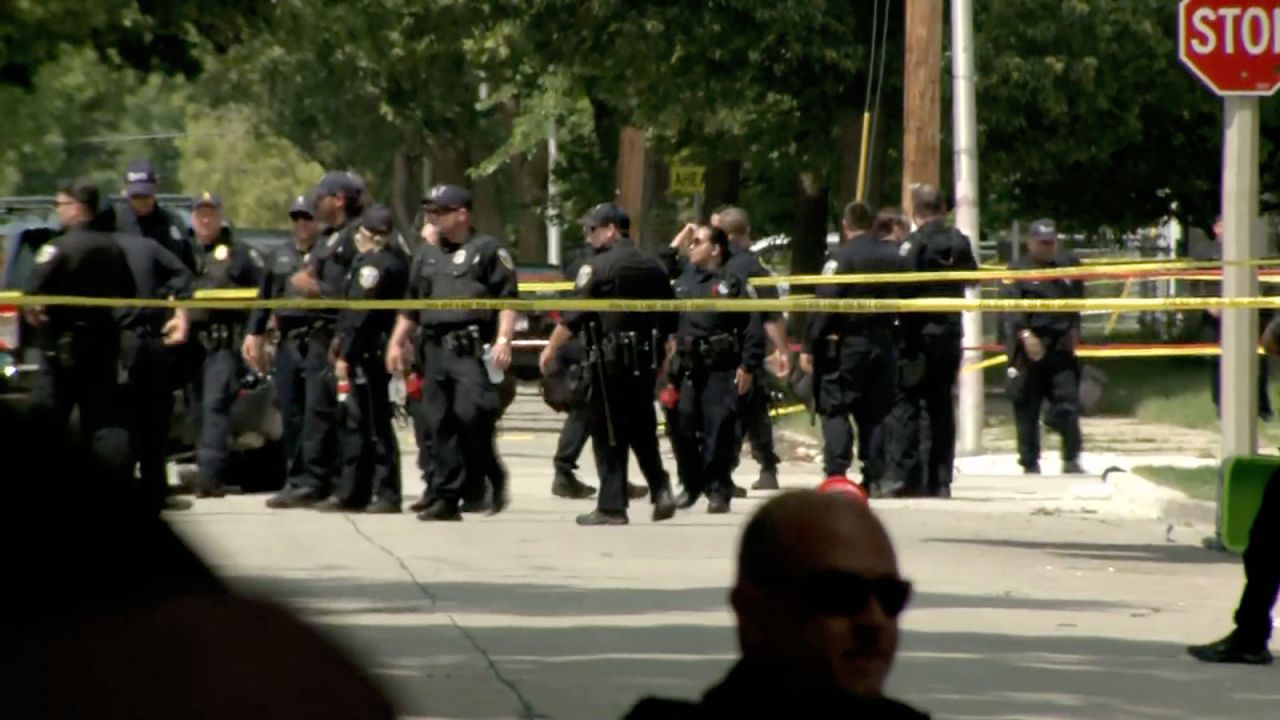 Miembros de las fuerzas del orden se reúnen cerca de donde los agentes dispararon al hombre. (WISN)