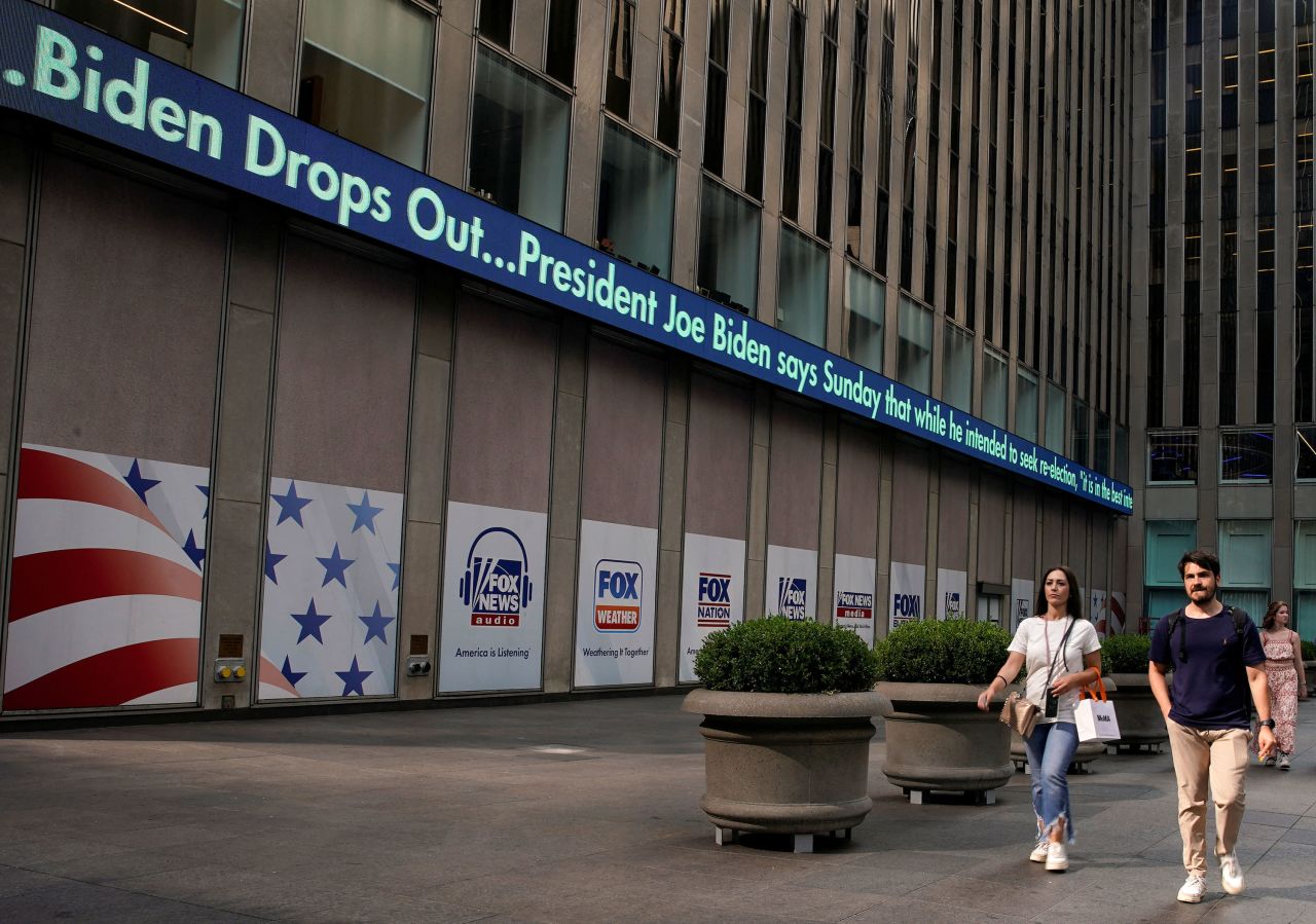 People walk near a a news ticker announcing that US President Joe Biden is dropping his reelection bid in the Manhattan borough of New York City on Sunday. 