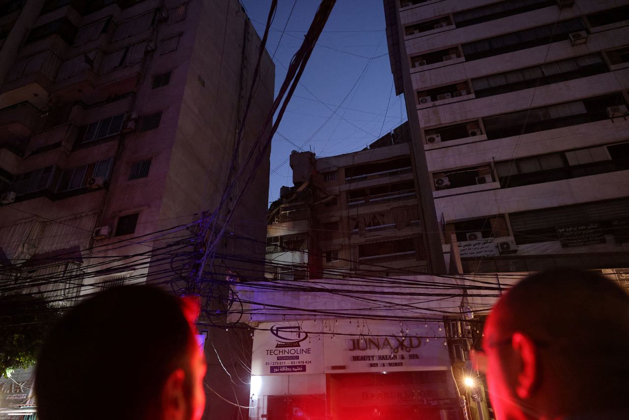 People look up at the destroyed top floors of a building following an Israeli strike on Beirut's southern suburb on Tuesday. 