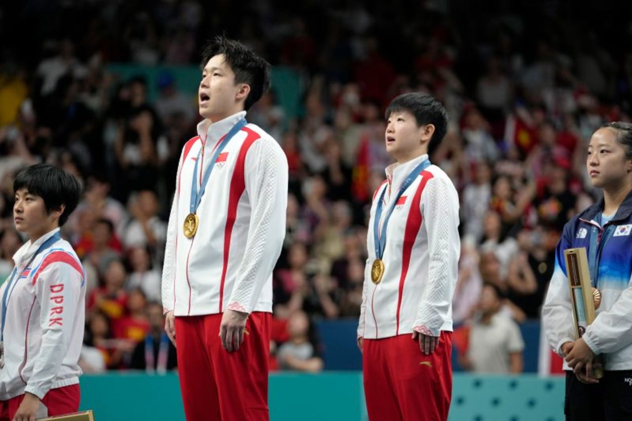 China's Wang Chuqin, second left, and Sun Yingsha sing their country's national anthem during the medal ceremony for table tennis in Paris, on July 30.