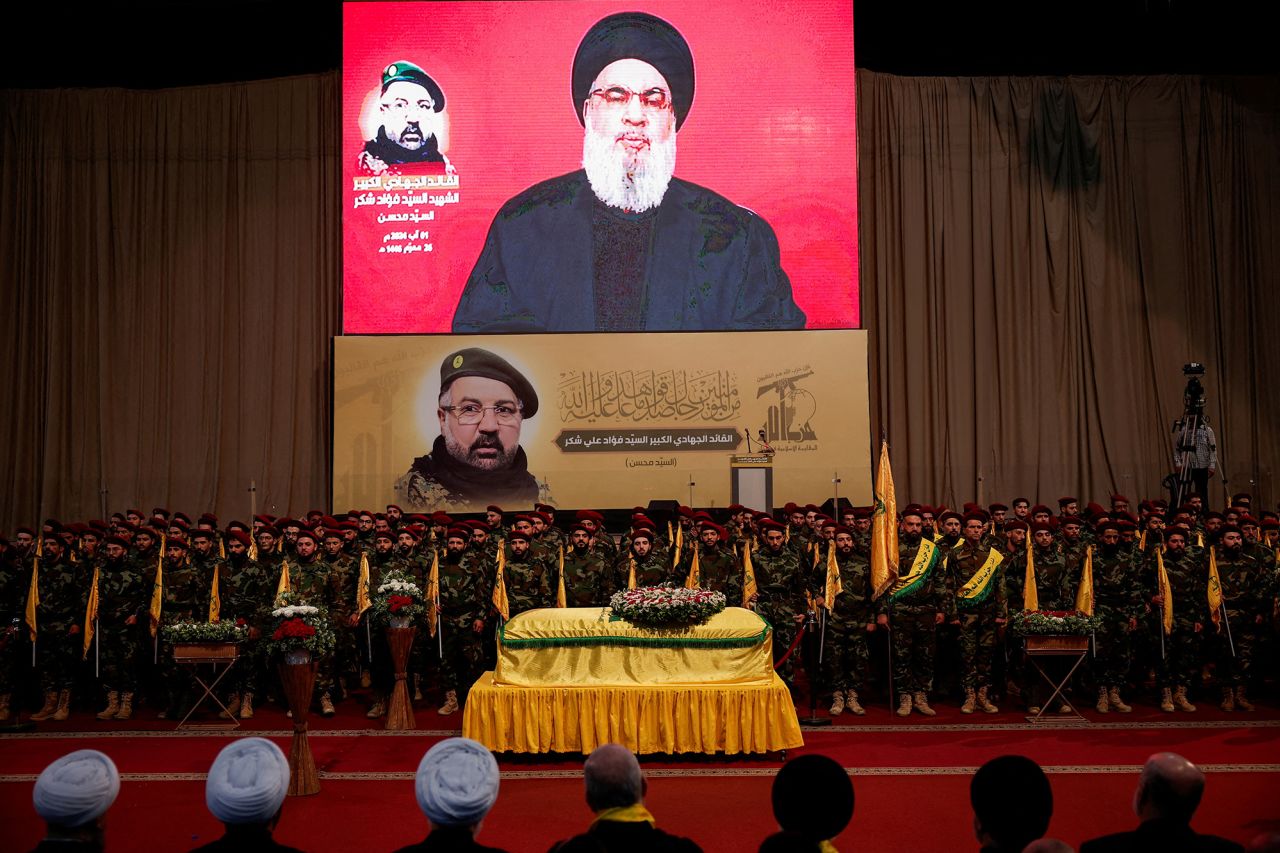 Hezbollah leader Hassan Nasrallah appears on a screen as he addresses his supporters, during the funeral of Hezbollah senior commander Fuad Shukr, in Lebanon on August 1. 