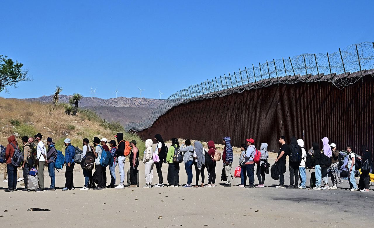 Migrants wait in line hoping for processing from Customs and Border Patrol agents after groups arrived at Jacumba Hot Springs, California, after walking under intense heat from Mexico into the US on June 5.