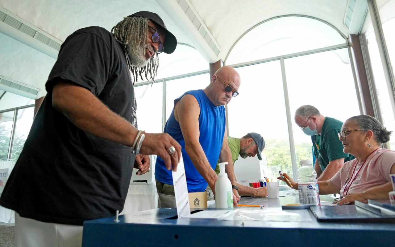 Rev. Gregory Lewis, left, of Milwaukee, drops his ballot in the ballot box while early voting at the Frank P. Zeidler Municipal Building on North Broadway in Milwaukee on Tuesday, July 30.