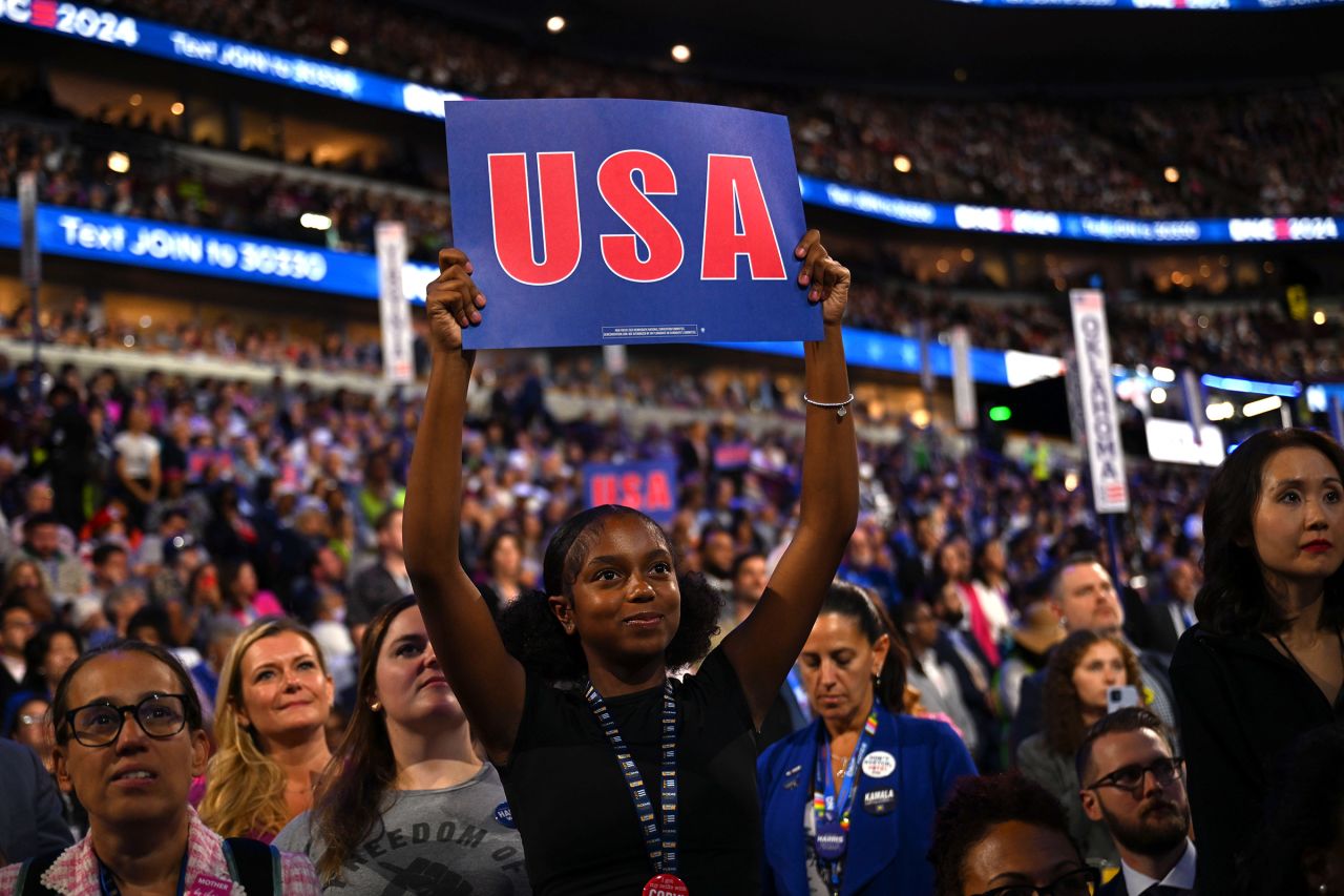 Rowan Curry holds up a USA sign on the convention floor at Chicago's United Center.