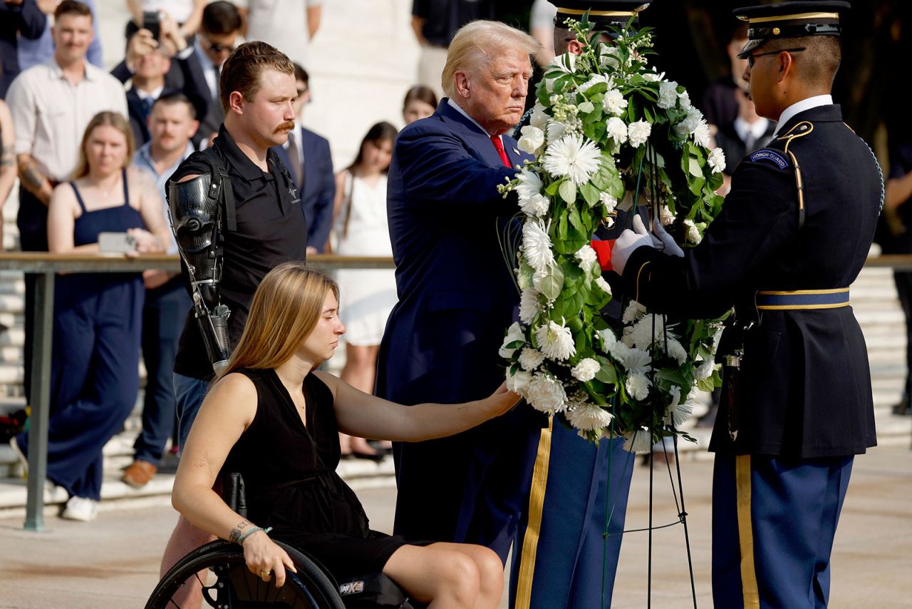 Former President Donald Trump lays a wreath alongside retired Marine Cpl. Kelsee Lainhart and retired US Marine Corps. Sgt. Tyler Vargas-Andrews during a wreath-laying ceremony at the Tomb of the Unknown Soldier at Arlington National Cemetery on Monday, August 26, in Arlington, Virginia. 