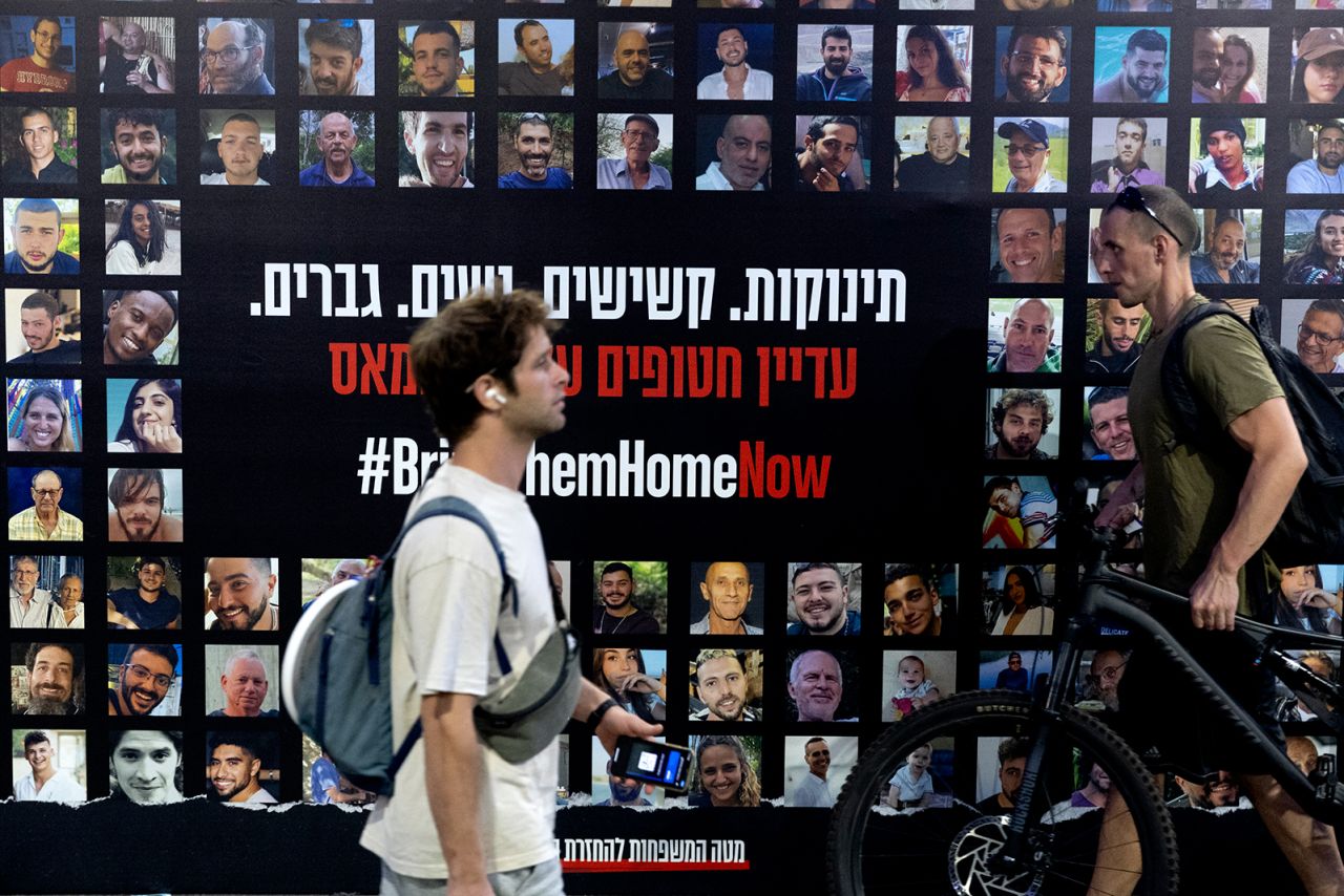 People at a train station in Tel Aviv walk by a poster covered with photos of hostages held in Gaza on August 24.