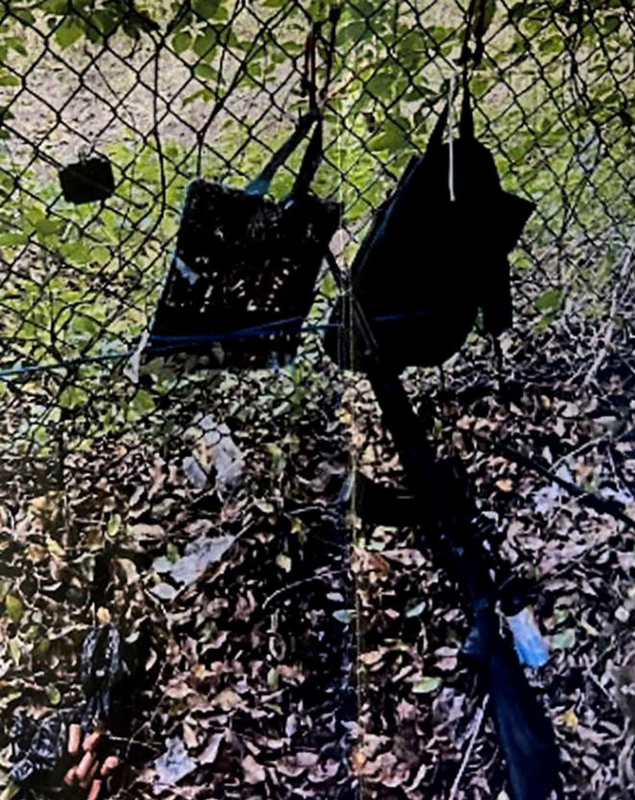 Bags hang from a fence over a rifle propped against it after the Secret Service foiled what the FBI called an apparent assassination attempt on former President Donald Trump while he was golfing on his course in West Palm Beach, Florida, on September 15.