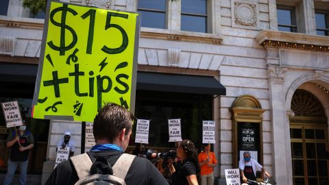 In this May 26, 2021, file photo, an activist holds up a sign outside Old Ebbitt Grill restaurant during a "Wage Strike" demonstration in Washington. 