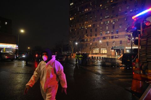 A worker who clean debris walks outside the scene after a deadly fire at an apartment building in the Bronx, on Sunday.