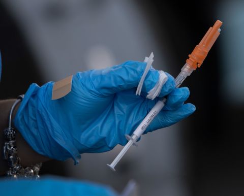 A healthcare worker prepares to administer a Pfizer-BioNTech COVID-19 vaccine to a person at a drive-thru site in Tropical Park on December 16, 2021, in Miami.
