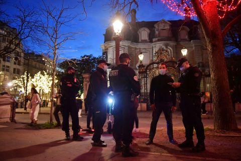 Police officers check compliance with the mandatory wearing of face masks, along the Champs-Elysees Avenue in Paris on New Year's Eve.