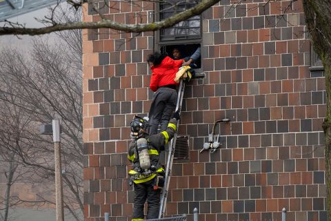 Firefighter rescues people after a fire broke out in a building located in the Bronx, on Sunday. 