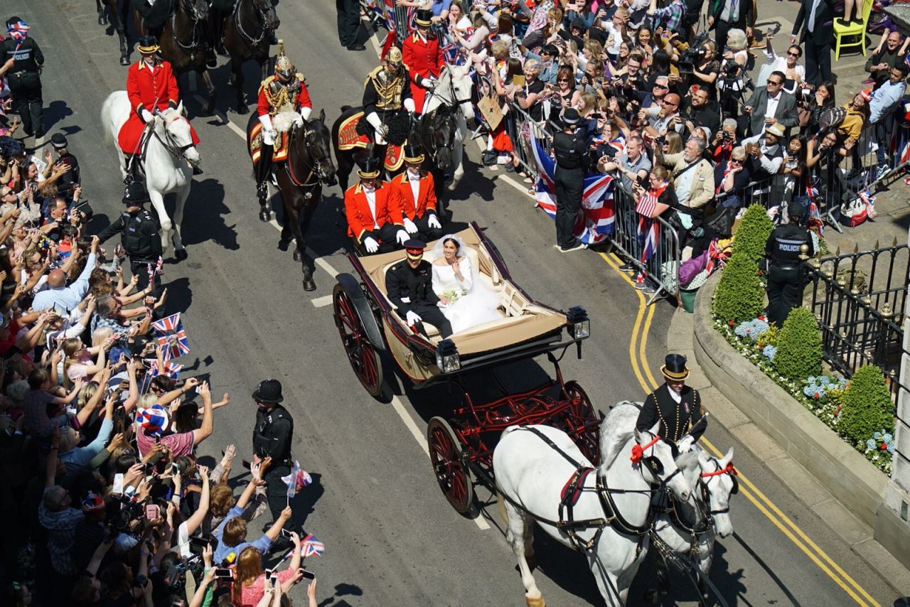 The Duke and Duchess of Sussex wave to the waiting crowds as they depart Windsor Castle. 