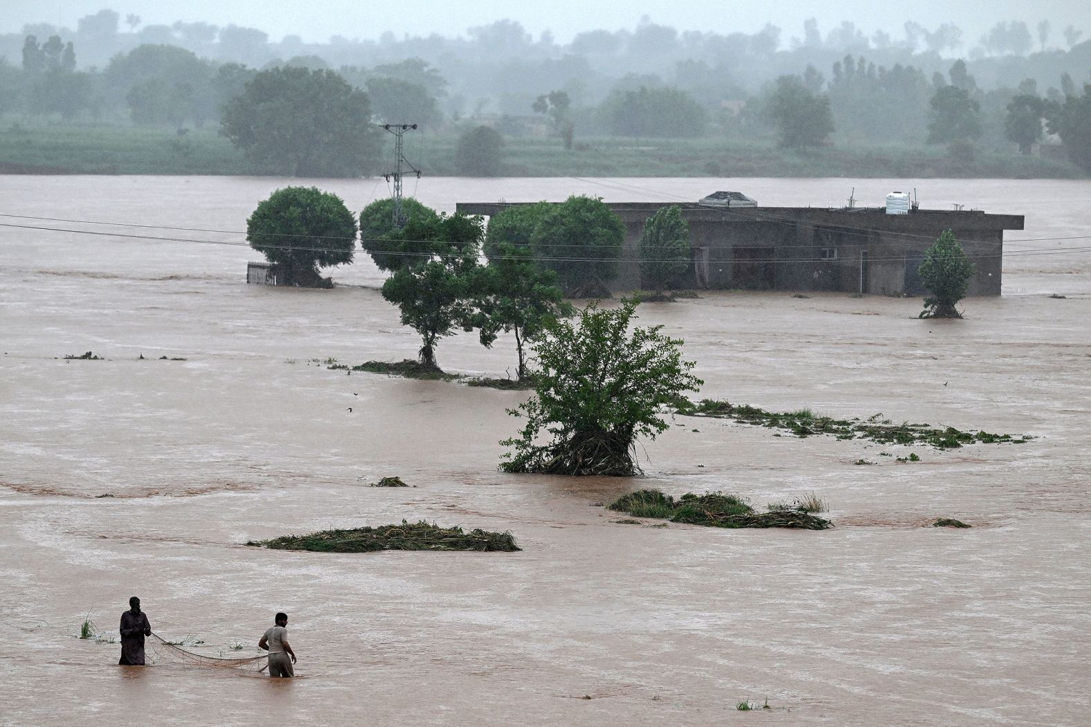 Local fishermen in floodwaters near a partially submerged house during heavy monsoon rains in Rawalpindi, a city in Punjab Province, Pakistan on July 17.