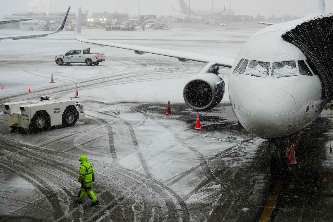 A man walks near a waiting plane as snow falls at John F. Kennedy International Airport in New York.