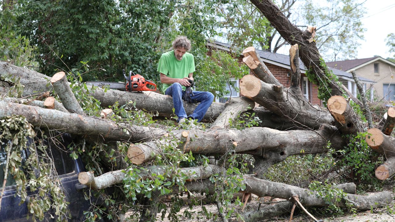 Andy Brown takes a break on top of what remains of a tree that destroyed his SUV when it fell during Hurricane Helene in Augusta, Georgia, on Tuesday.