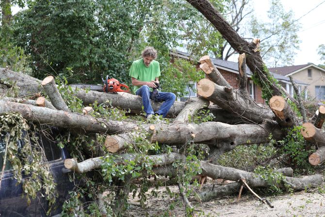 Andy Brown takes a break on top of what remains of a tree that destroyed his SUV in Augusta, Georgia, on Tuesday.