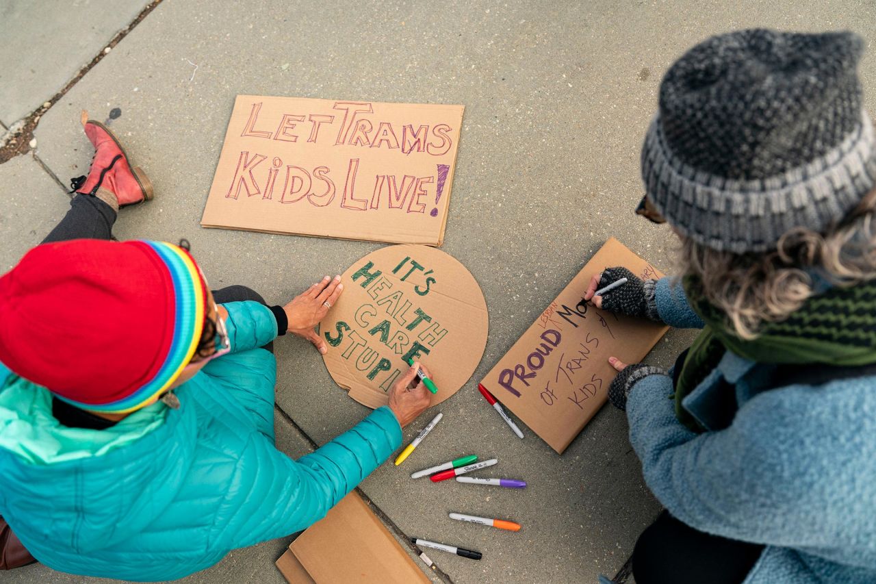 Demonstrators in support of gender-affirming treatment make signs outside the US Supreme Court.