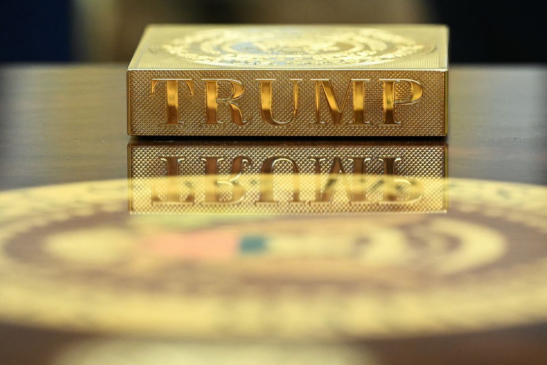 Um peso de papel dourado fica sobre a mesa em frente a Trump.