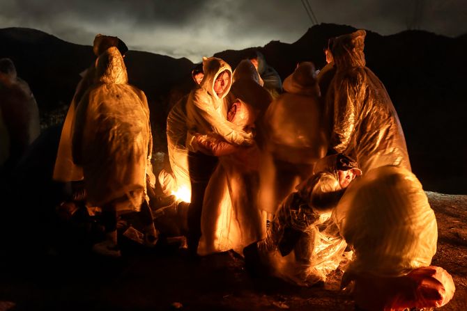 <strong>"Night Crossing."</strong> <a href="index.php?page=&url=https%3A%2F%2Fwww.cnn.com%2F2024%2F01%2F08%2Famericas%2Fchina-us-migrants-illegal-crossings-intl-hnk-dst%2Findex.html">Chinese migrants</a> warm themselves during a cold rain after crossing the US–Mexico border in Campo, California, on March 7, 2024. Finalist, World Press Photo of the Year.