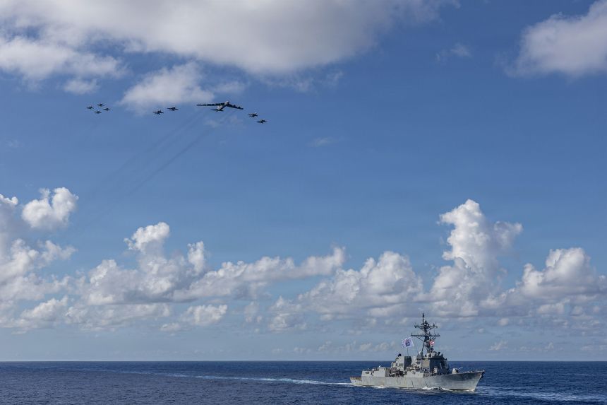 A F/A-18E Super Hornet aircraft attached to the Gerald R. Ford Strike Group and a US Air Force B-52H Stratofortress fly over Arleigh Burke-class guided-missile destroyer USS Bainbridge in the western Atlantic Ocean on November 13.