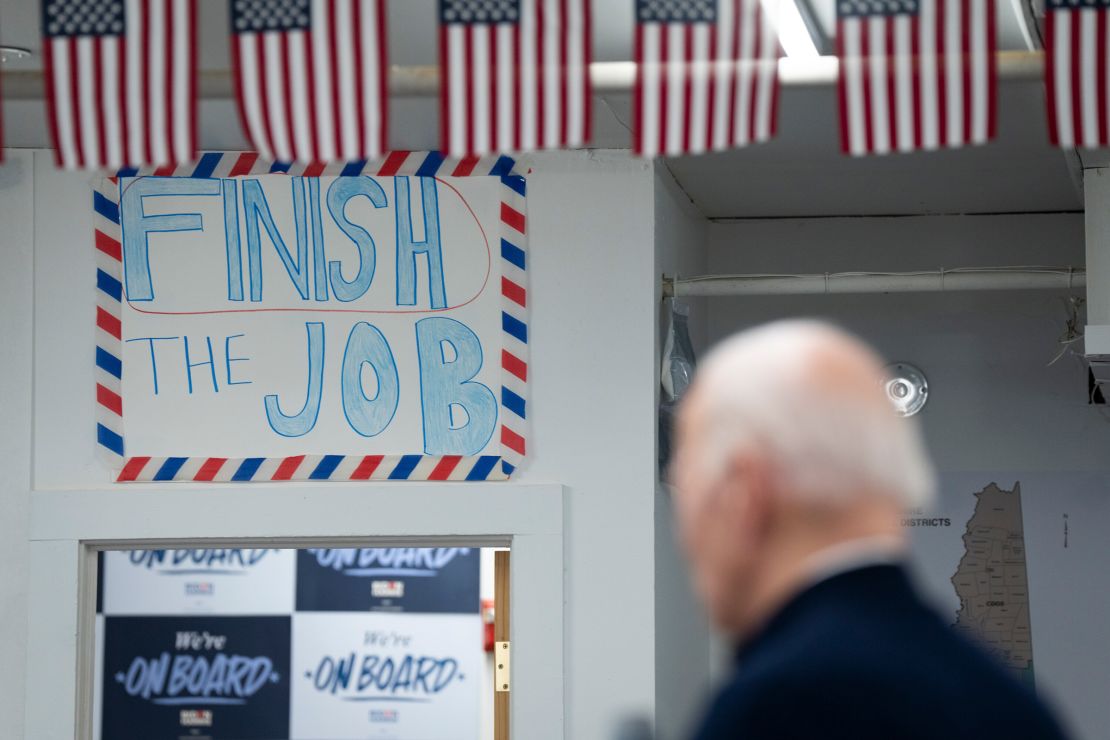 A poster reading "Finish the Job" hangs on the wall as President Joe Biden speaks during a visit to a field office for his presidential campaign in Manchester, New Hampshire, on March 11.