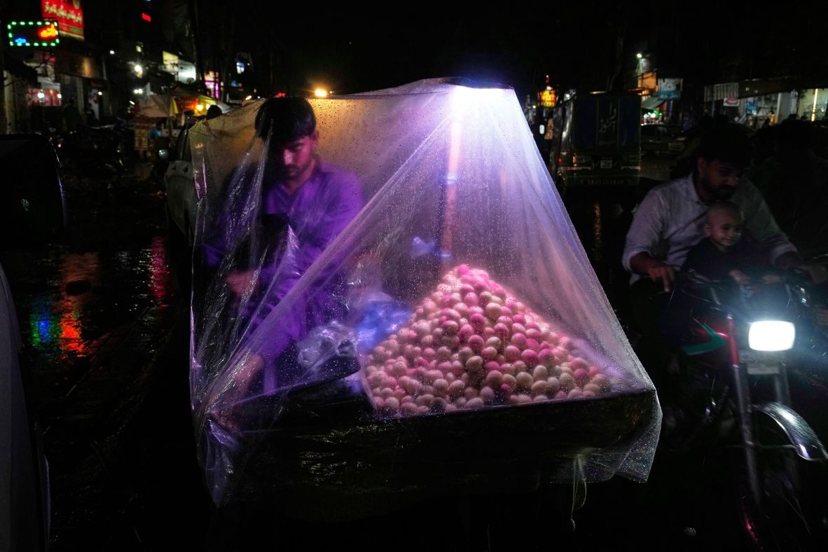 A street vendor protects himself and his goods with a plastic sheet during a rain storm in Lahore, Pakistan, on July 15.