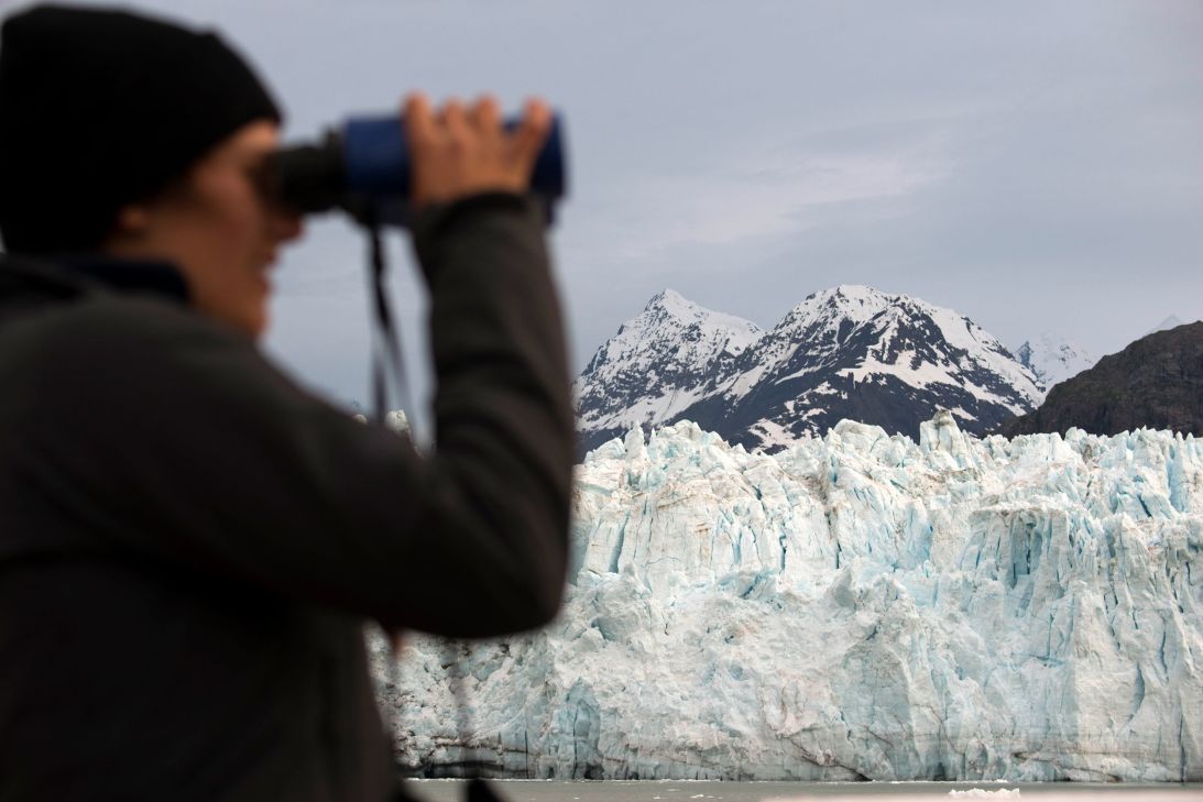 A crew member looks through binoculars on cruise ship Safari Endeavour in front of Margerie Glacier in Glacier Bay National Park.