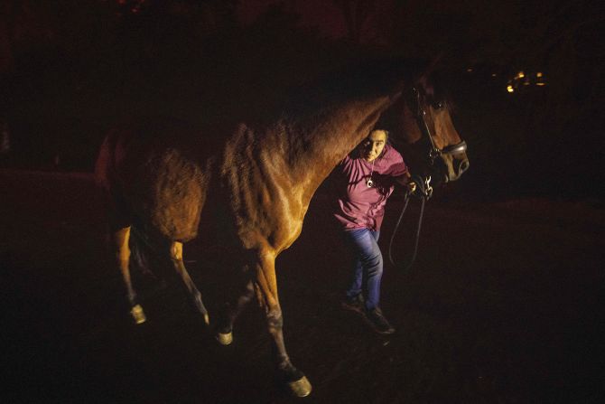 A woman helps a horse evacuate the area on Tuesday.