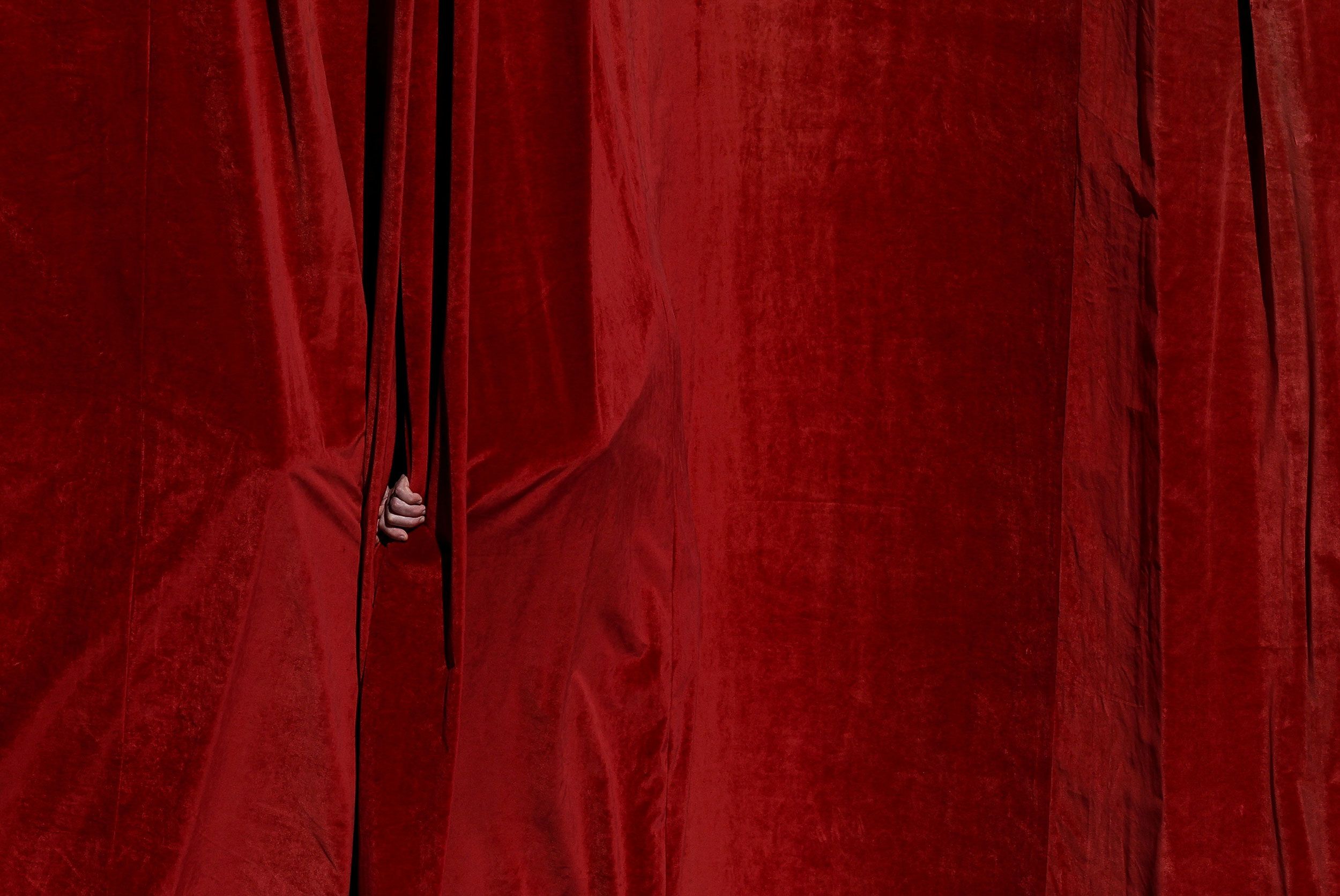 A person peeks through a curtain during the funeral.