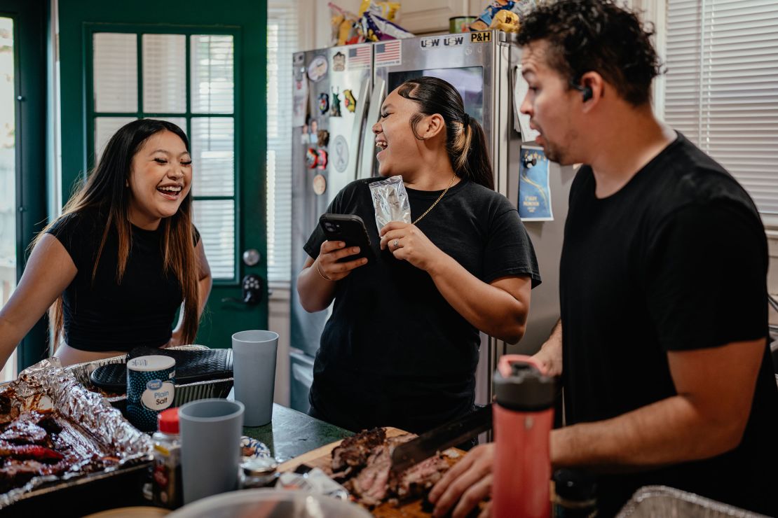 From left, Azia Yang, 23, Fantazia Lor, 18, and Michael Bub Jr. video chat with Ma Yang to show her the dinner they made as a family in West Milwaukee, Wisconsin.