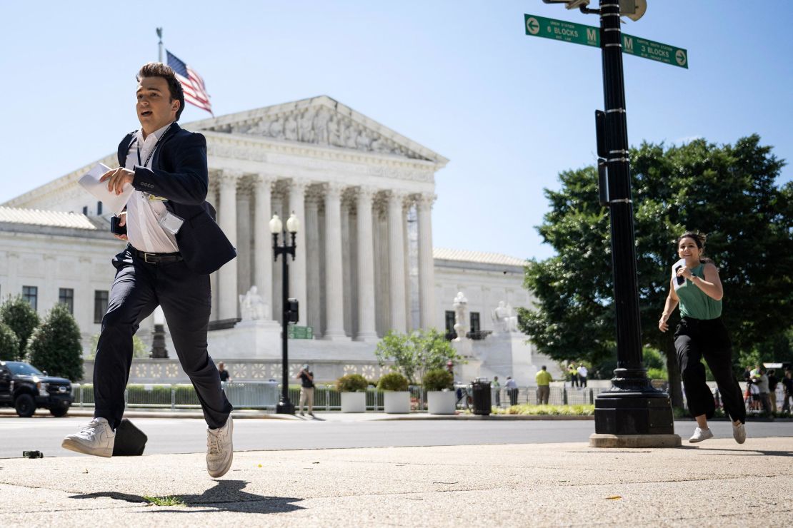 A journalist runs across the US Supreme Court plaza carrying an opinion to a news correspondent as the court handed down decisions on July 1, 2024, in Washington, DC. 