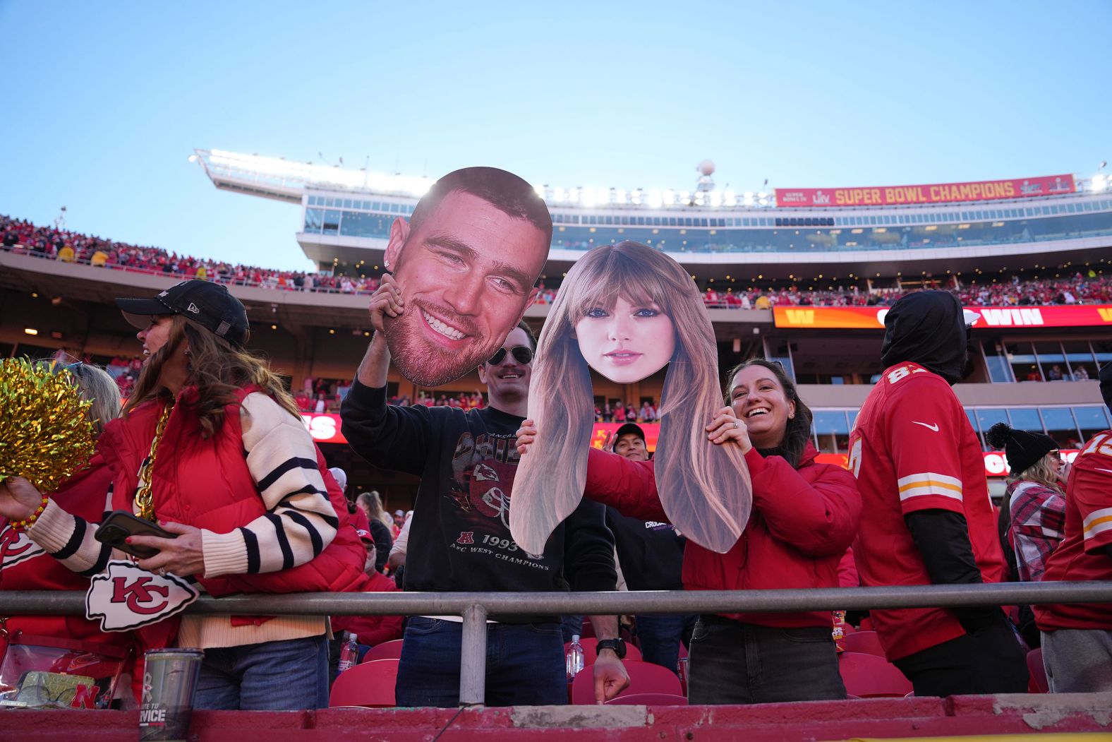 A Chiefs fan holds cutout faces of the celebrity couple in November 2024.