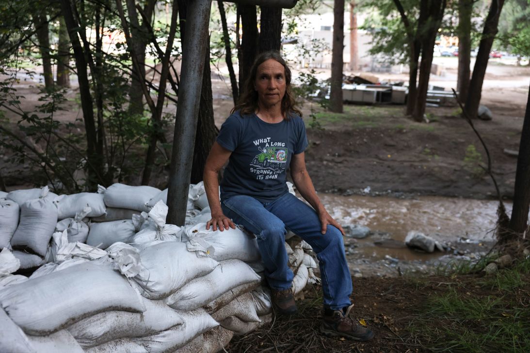 Nancy Crownover sits on sandbags outside her house along the Rio Ruidoso on August 27.