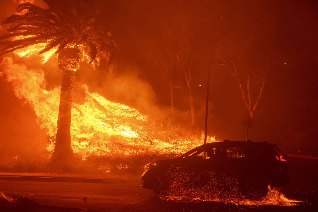 A car drives past flames from the Franklin Fire at Pepperdine University.