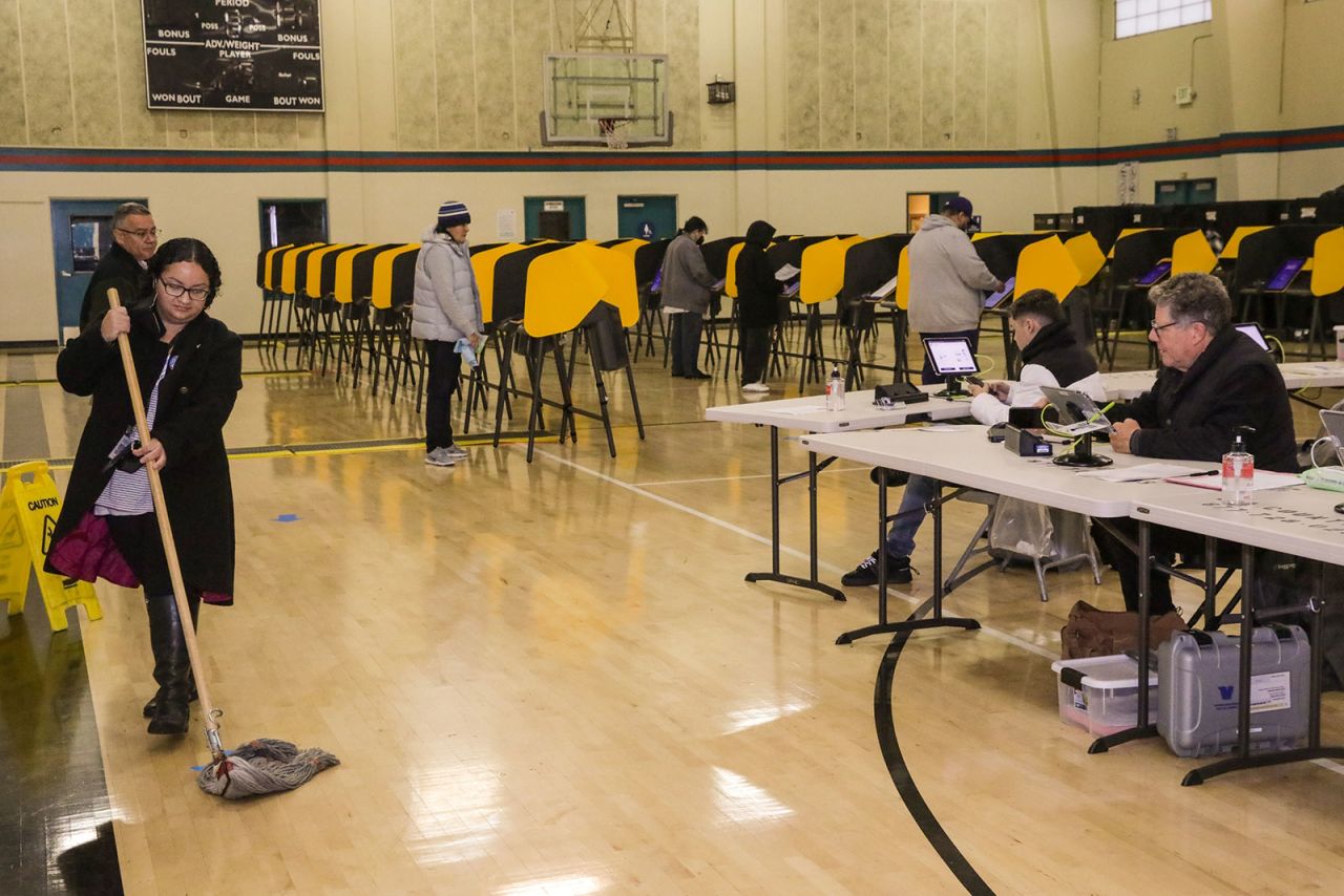 Jenny Reyes, a polling station worker, keeps slippery floor dry as voters walk in to cast their ballots on a rainy day in Los Angeles on November 8.