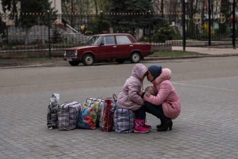A mother hugs her daughter as they wait for a bus to flee from Sloviansk, on Saturday, April 16, 2022.