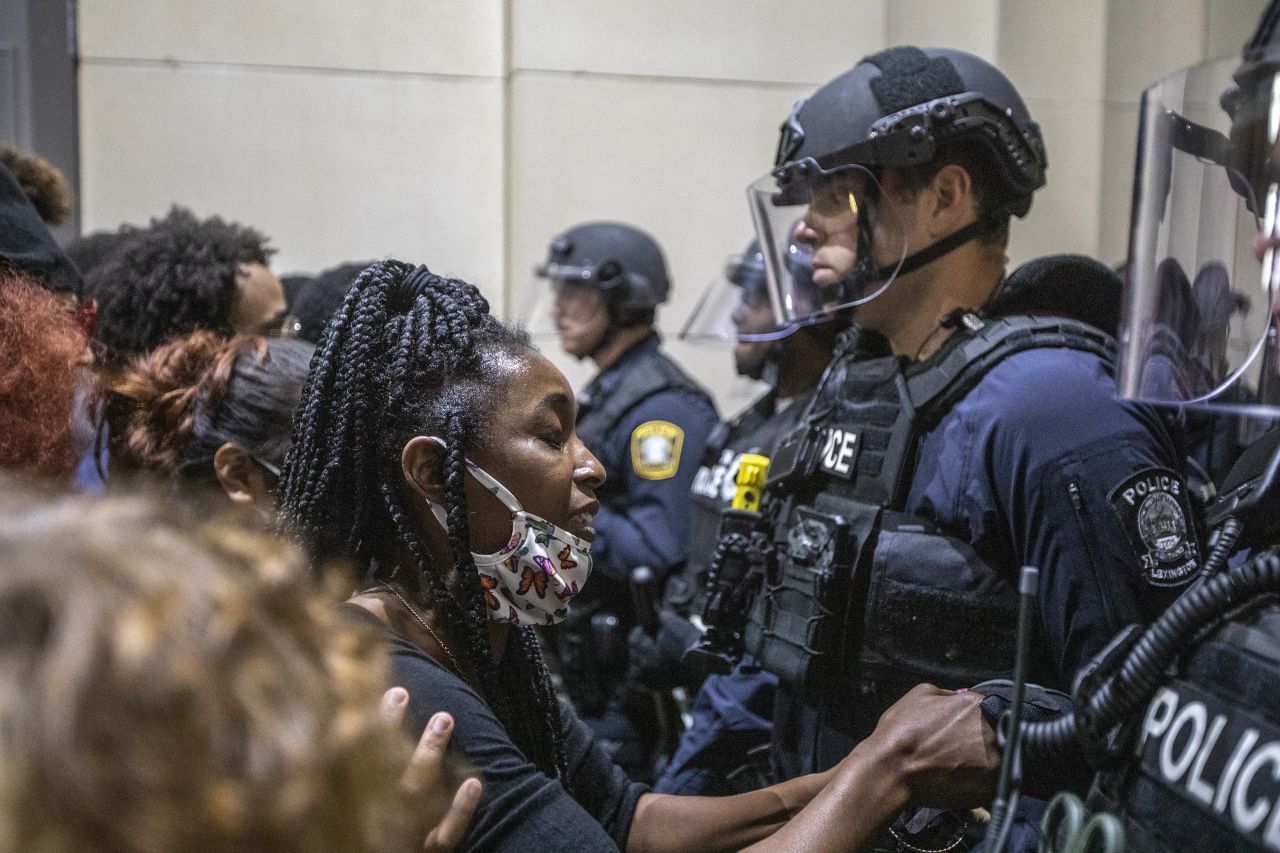 A protester holds a police officer's hand while praying together during a rally to protest the deaths of George Floyd and Breonna Taylor in Lexington, Kentucky, on Sunday, May 31. 