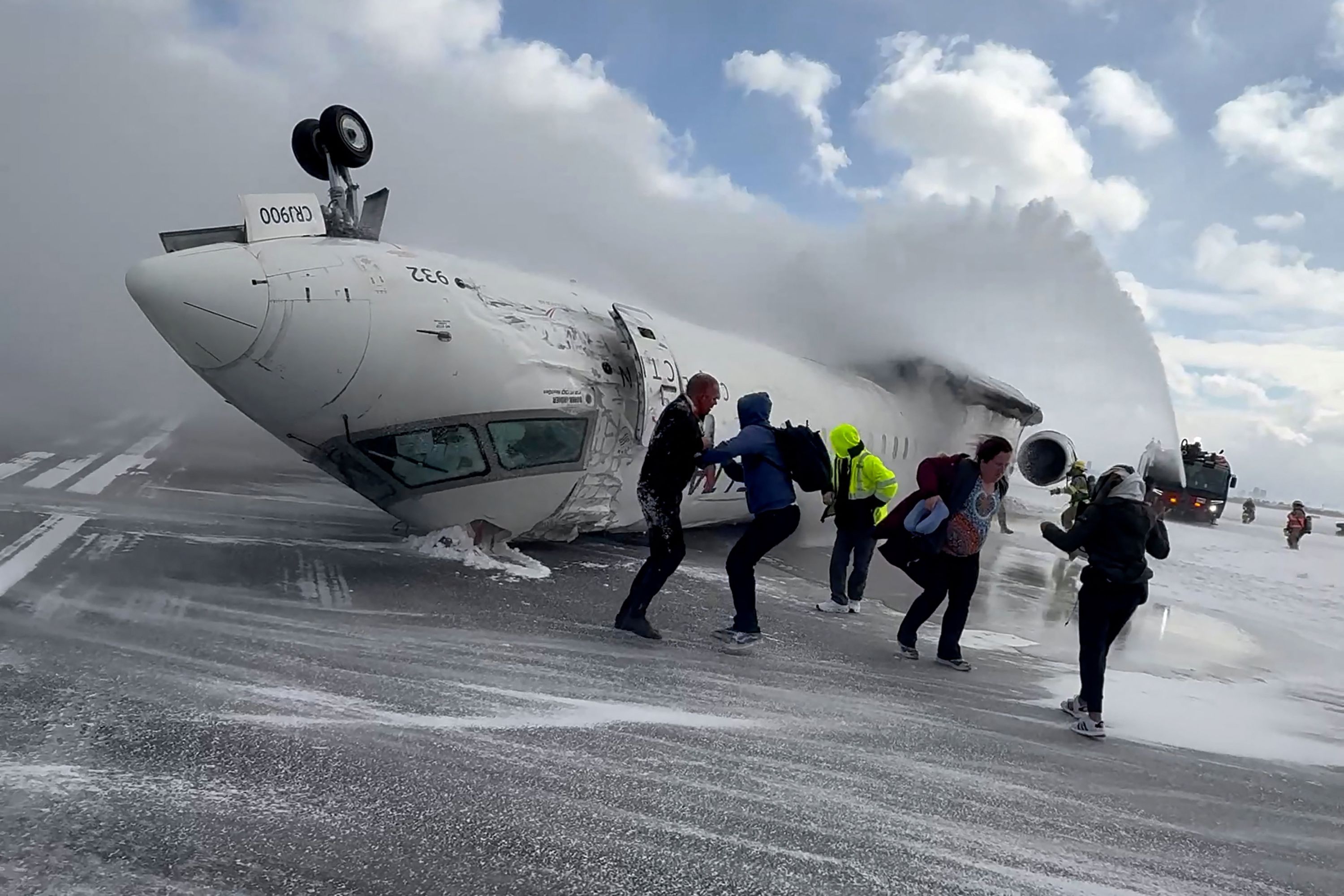 In this image taken from video, passengers walk away from a Delta Air Lines jet that crash-landed at Toronto Pearson International Airport on Monday, February 17.