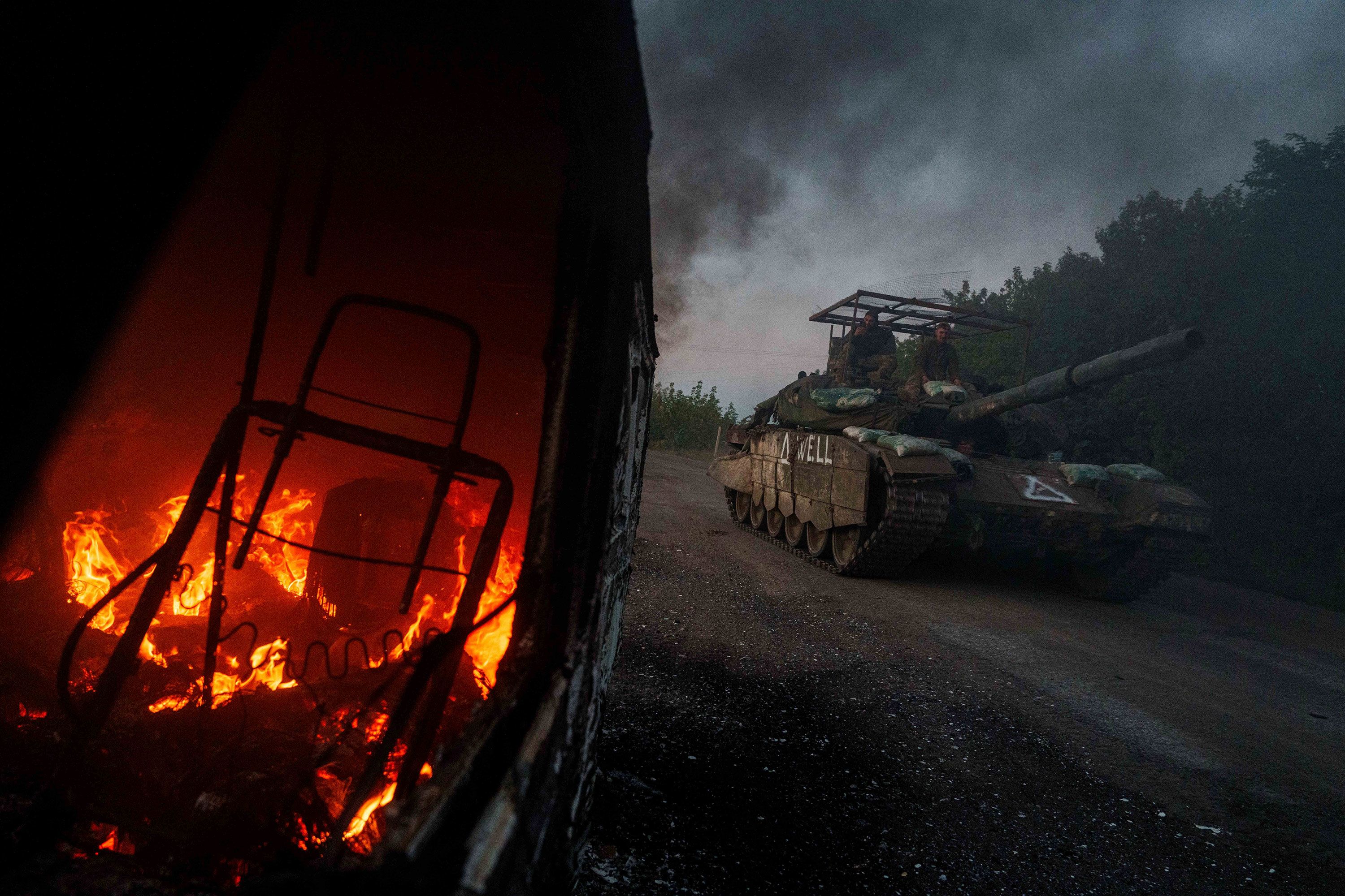 A Ukrainian tank passes by a burning car in Ukraine’s Sumy region, near the border with Russia, on Wednesday, August 14.