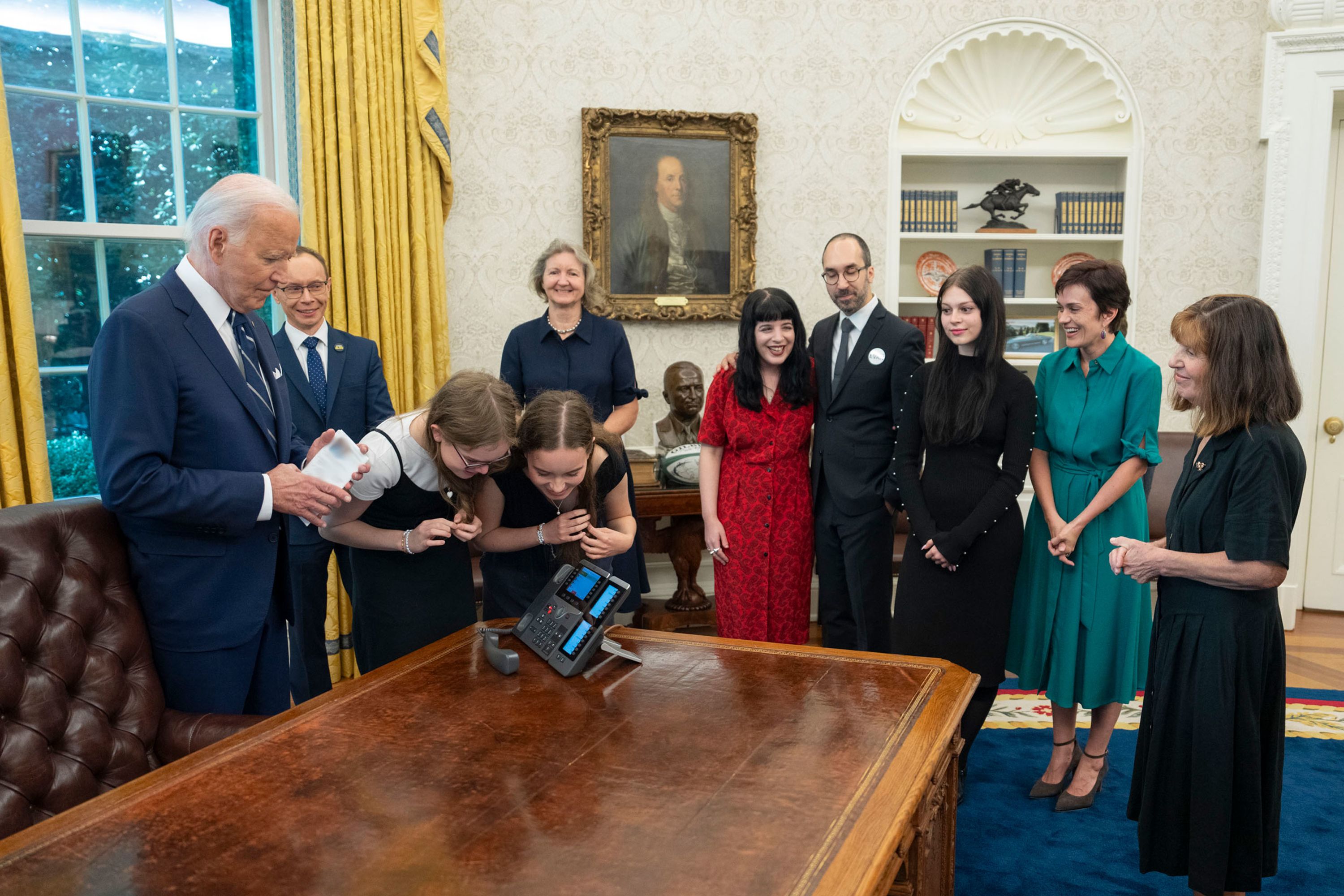 US President Joe Biden is joined in the White House Oval Office by family members of prisoners who were released by Russia on Thursday, August 1. <em>(Editor’s note: The document in Biden’s hand was obscured by the White House.)</em>