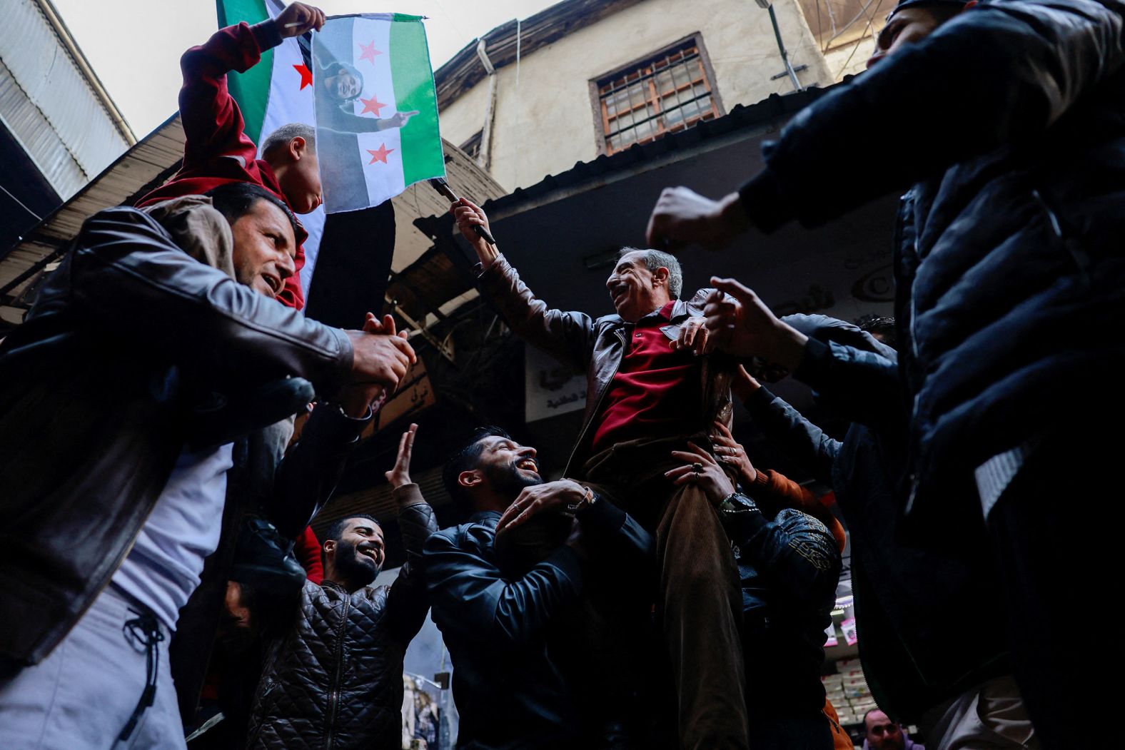 People celebrate the ouster of Bashar al-Assad at a marketplace in Damascus on December 12.