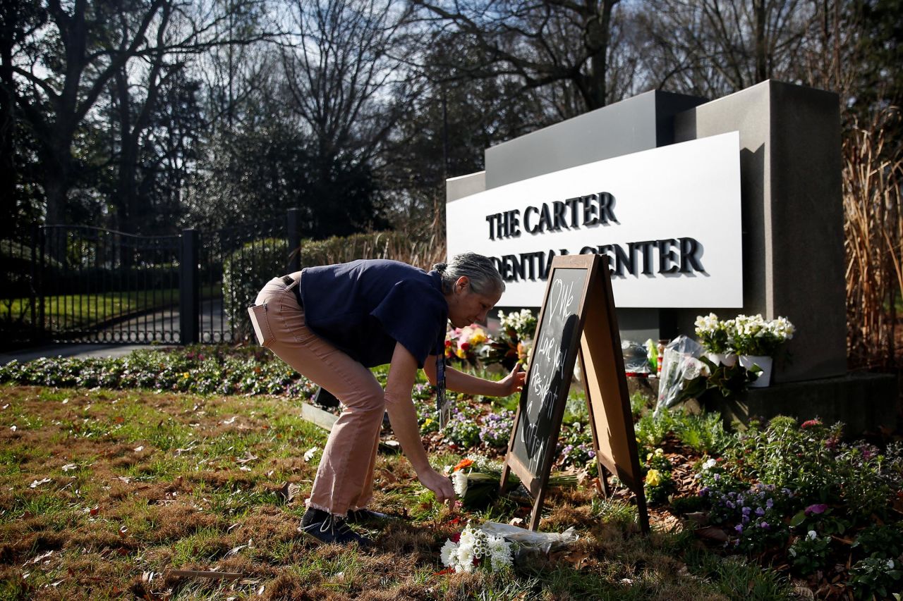 Denise Bomberger, a volunteer with The Carter Presidential Center, organizes mementos left by mourners paying tribute to the life and legacy of former President Jimmy Carter in Atlanta on December 30.