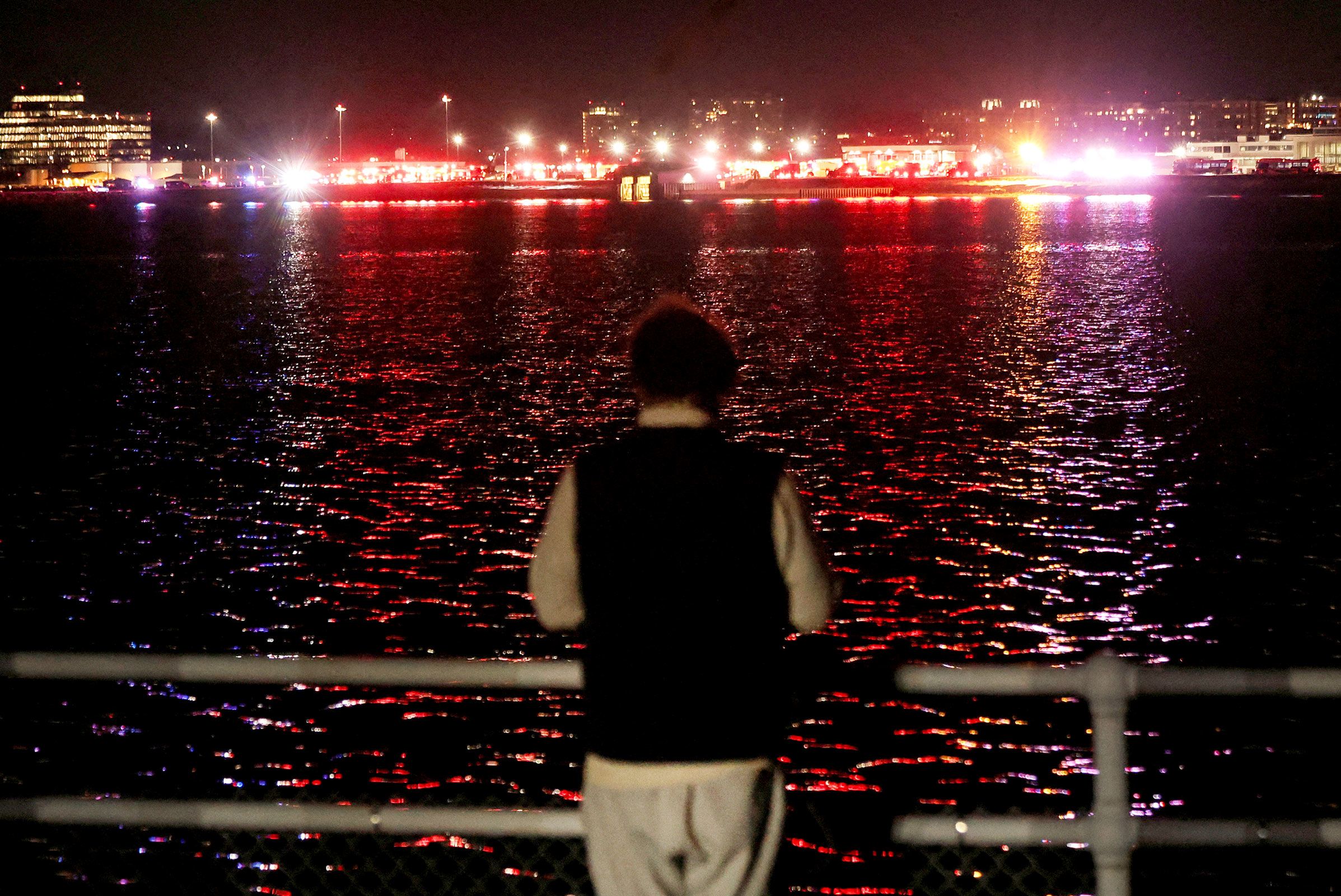 A person watches emergency service vehicles operate near the site of the crash on Wednesday, January 29.