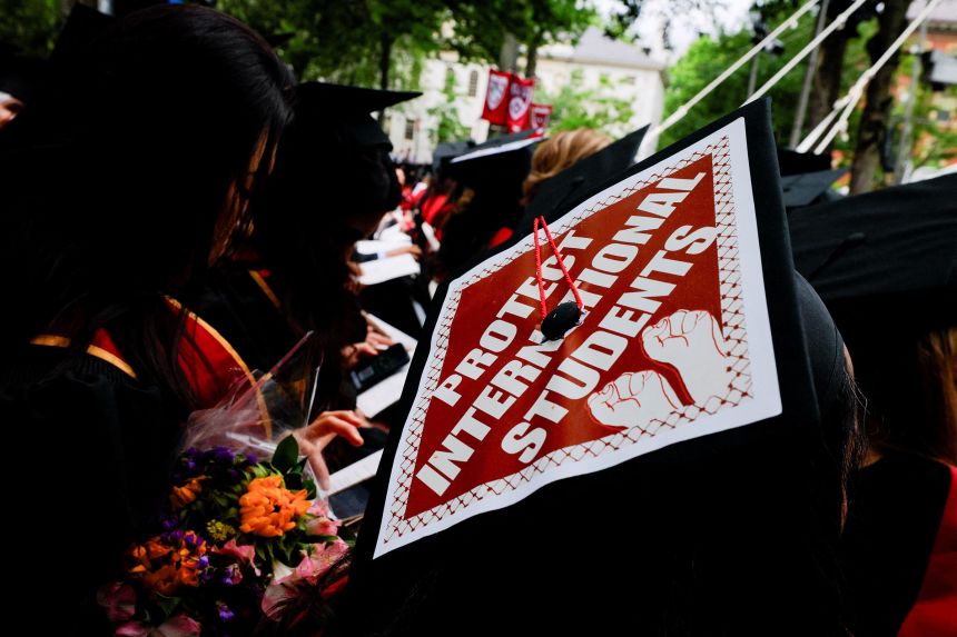A graduating student wears their hat, decorated with a statement of support for international students, during commencement exercises Thursday at Harvard University.