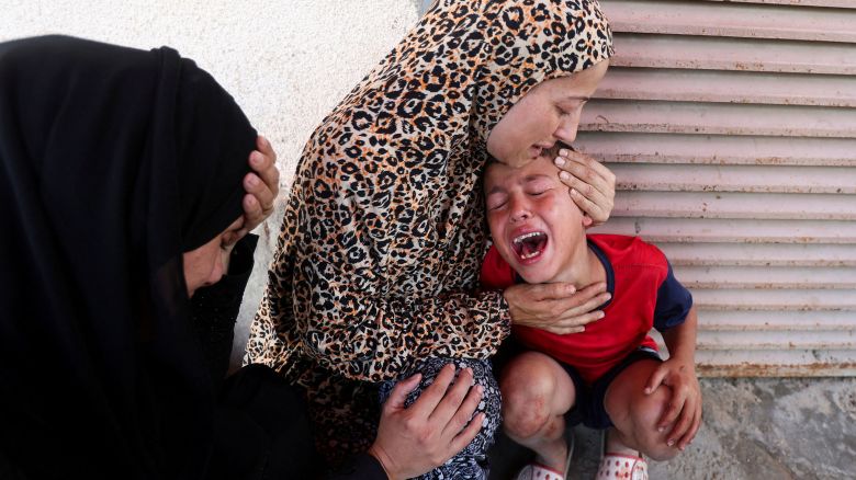 A Palestinian woman comforts a child as casualties are brought into Al-Aqsa Martyrs Hospital following an Israeli strike, in Deir al-Balah, central Gaza Strip, July 10, 2025.